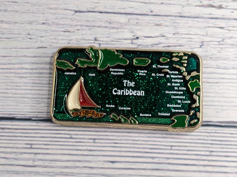 A rectangular silver metal magnet with a green enamel depiction of the Caribbean Islands.